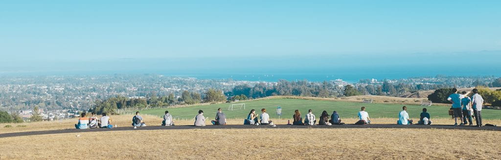 students sitting in a field on campus
